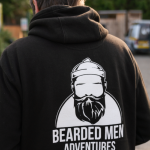 man wearing black hooded jumper with white bearded men adventures logo.